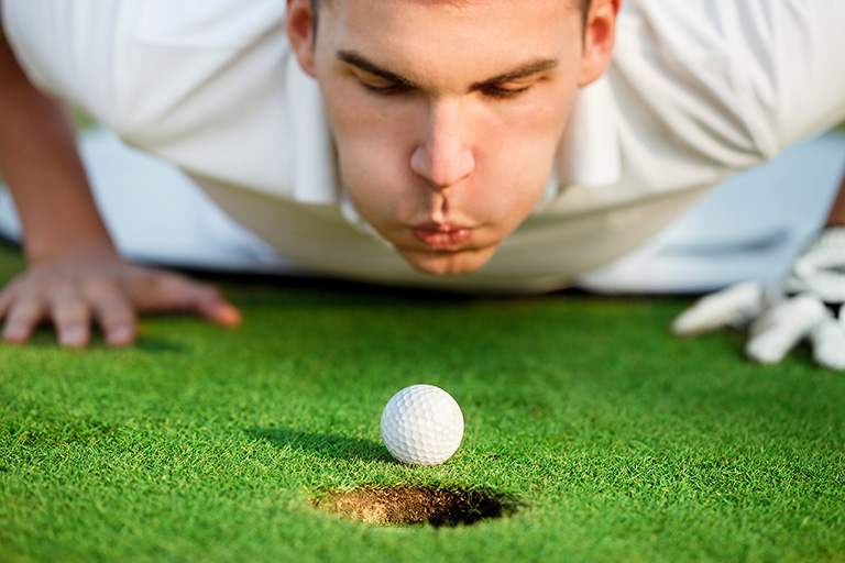 golfer lying on grass and blowing in the ball, just need to give it a little help.